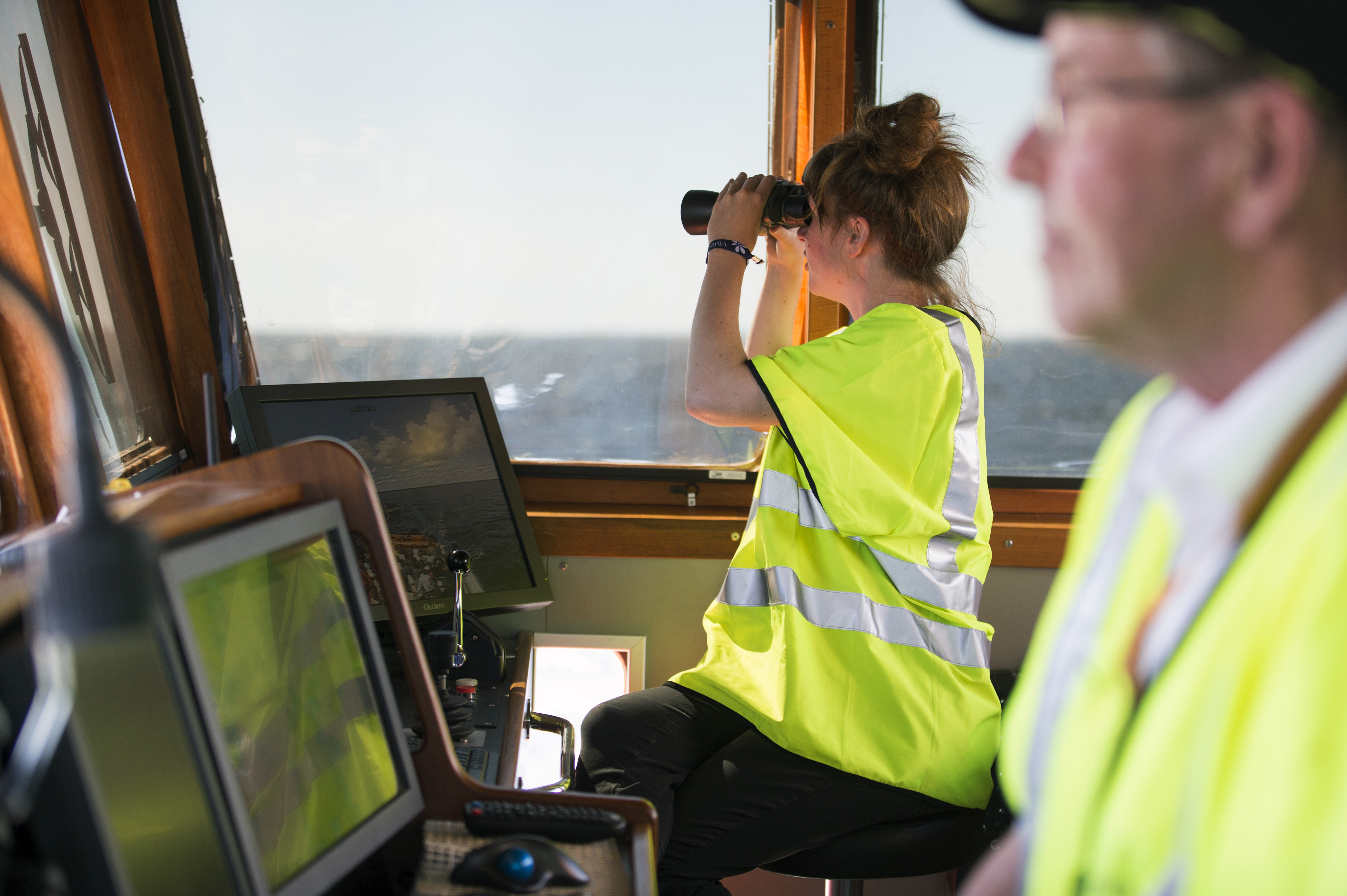 Kvinna med kikare ser ut genom fönster